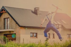 Handwerker springt vor fertigem Haus vor Freude in die Luft