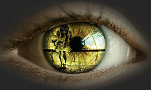 In der Iris eines Auges ist ein misshandeltes Kind zu sehen, welches zusammen gekauert auf einer Bank sitzt