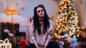 Grübelnde und traurig aussehende Frau vor Weihnachtsambiente. Sie ist abgewendet.