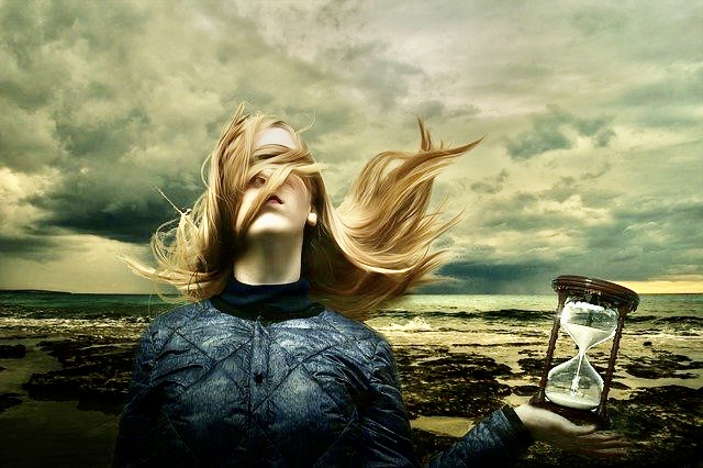 Traumsequenz, Frau mit ins Gesicht gewehten Haaren, mit Sanduhr im Hintergrund