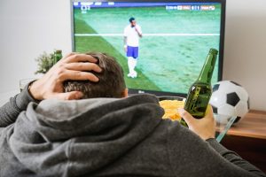 Mann rauft sich die Haare beim Fußball gucken im Fernsehen, Bier in der Hand